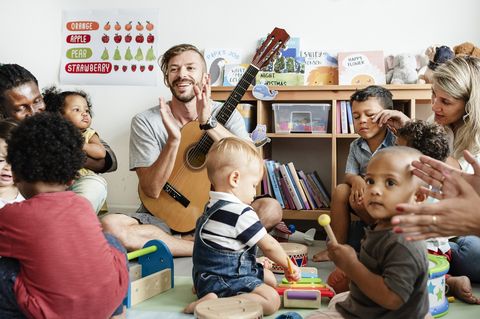 Ein Erzieher spielt Gitarre und macht mit Kindern Musik