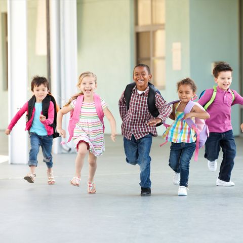 Kinder laufen mit Schultornistern durch ein Gebäude